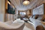 Luxury chalet living room with stunning mountain views, featuring a large sectional sofa, a statement coffee table, and a cozy fireplace.
