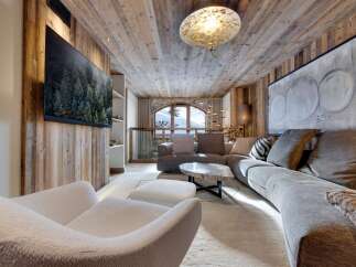 Luxury chalet living room with stunning mountain views, featuring a large sectional sofa, a statement coffee table, and a cozy fireplace.