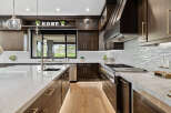 This stunning kitchen boasts a modern design with dark wood cabinetry, sleek gold hardware, and a large island with a marble countertop.