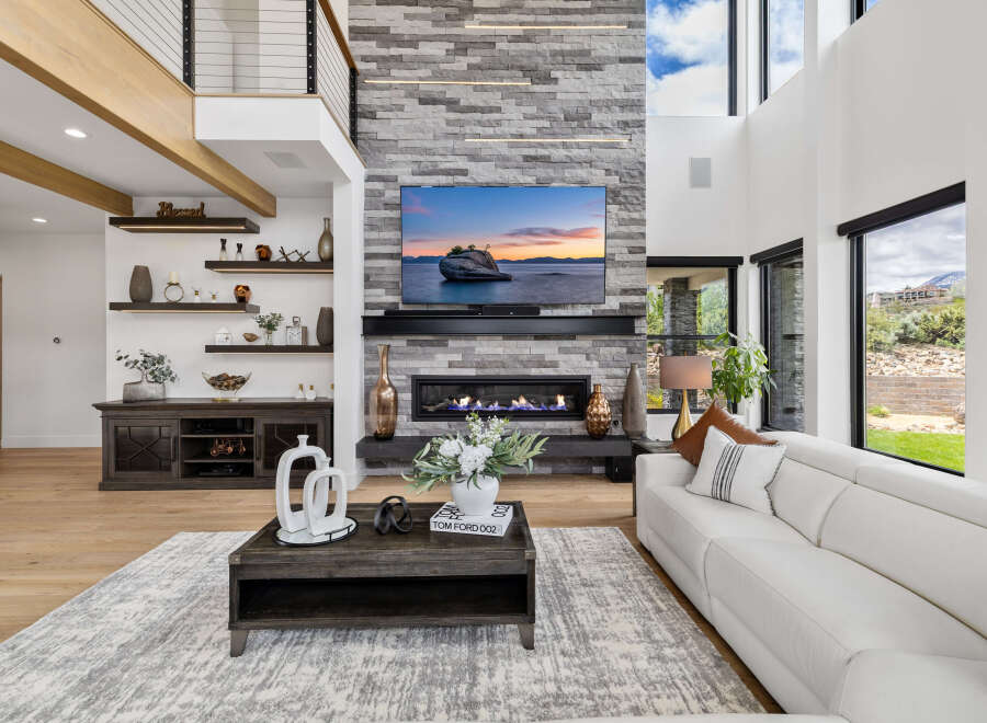 Stunning living room with a floor-to-ceiling stone fireplace, large windows offering scenic views, and a spacious, modern design.