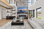 Stunning living room with a floor-to-ceiling stone fireplace, large windows offering scenic views, and a spacious, modern design.