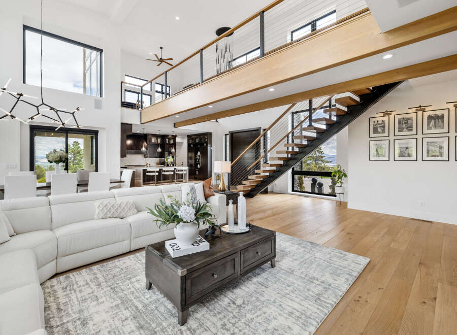 Stunning modern home with open concept living, featuring a sleek floating staircase and expansive windows offering breathtaking views.