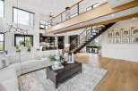 Stunning modern home with open concept living, featuring a sleek floating staircase and expansive windows offering breathtaking views.