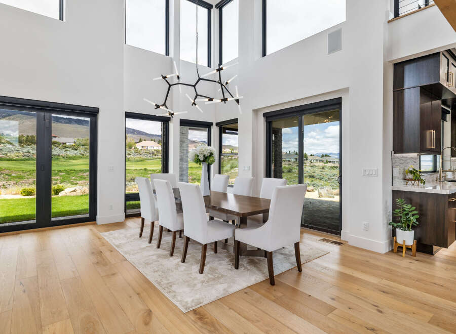 This stunning home boasts a spacious dining area with floor-to-ceiling windows offering breathtaking views.