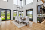 This stunning home boasts a spacious dining area with floor-to-ceiling windows offering breathtaking views.