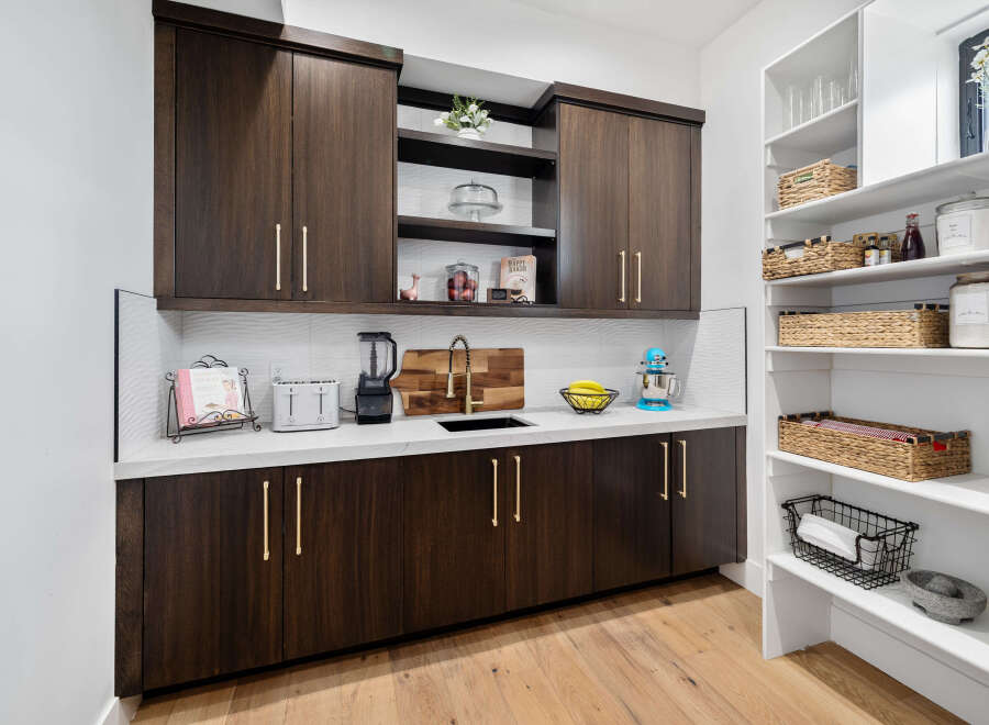 This stunning kitchen boasts a built-in pantry with ample shelving and stylish woven baskets for optimal organization.