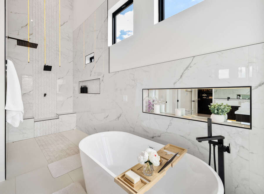 Luxurious bathroom boasts a freestanding tub, marble tile, and a walk-in shower with rainfall shower head.