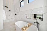 Luxurious bathroom boasts a freestanding tub, marble tile, and a walk-in shower with rainfall shower head.