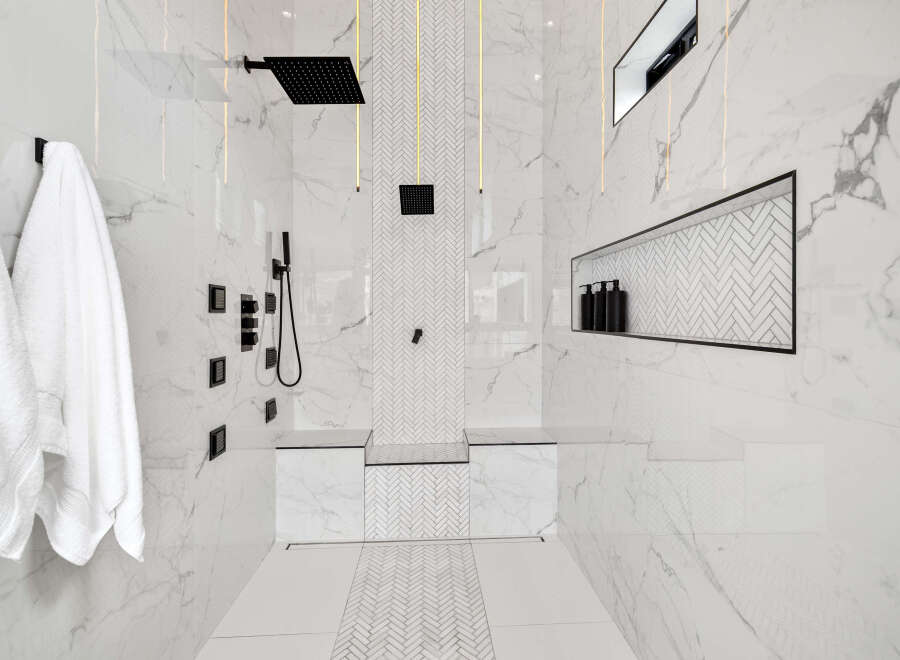 Luxurious bathroom with marble walls and herringbone patterned floor.