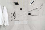 Luxurious bathroom with marble walls and herringbone patterned floor.
