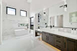 Luxurious master bathroom boasts a freestanding soaking tub, double vanity with dark wood cabinets, and marble tile.
