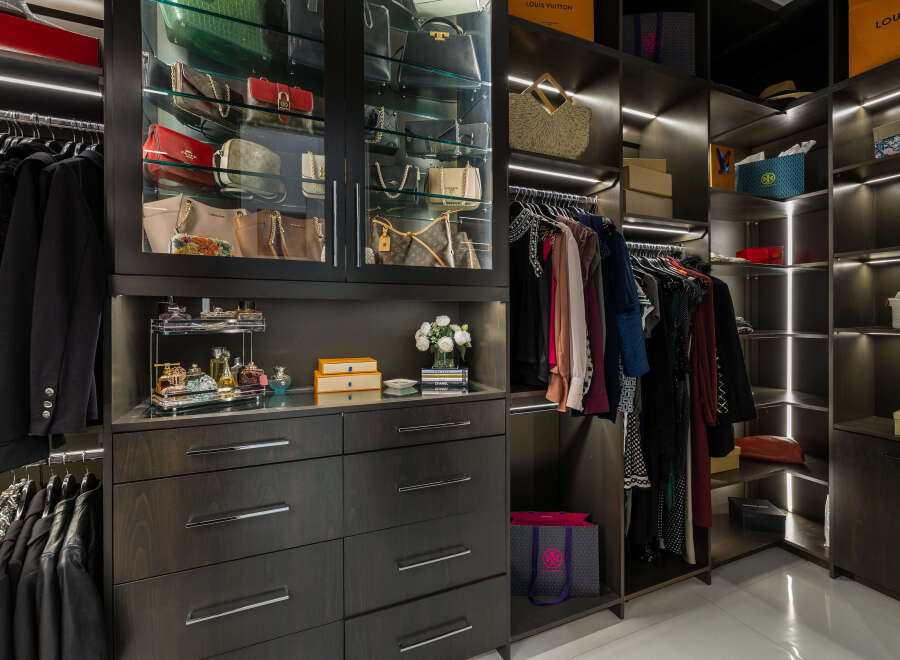 Luxury closet design featuring ample hanging space, glass-front cabinets for handbags, and built-in drawers for accessories.