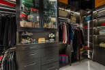 Luxury closet design featuring ample hanging space, glass-front cabinets for handbags, and built-in drawers for accessories.