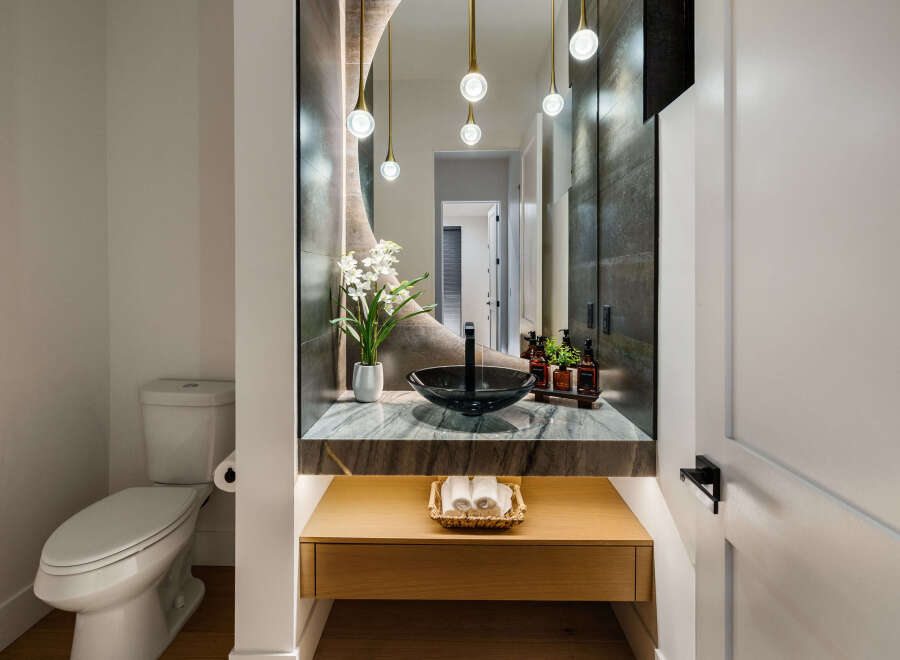 This stunning powder room boasts a modern design with a sleek black sink and marble countertop.