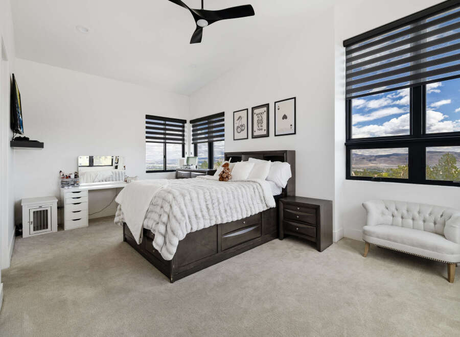 This stunning bedroom boasts large windows offering breathtaking views, complemented by stylish window shades.