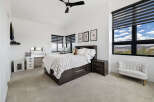 This stunning bedroom boasts large windows offering breathtaking views, complemented by stylish window shades.