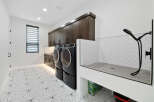 This stunning laundry room boasts modern dark wood cabinets, geometric patterned flooring, and a built-in pet washing station.