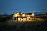 Stunning modern home nestled on a hillside, boasting expansive windows and a spacious backyard.