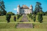 This majestic castle boasts a stunning facade, complemented by meticulously manicured gardens and a grand staircase leading to its entrance.