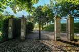 This property boasts a grand entrance with a stunning arched metal gate and stone pillars, creating an elegant and secure feel.