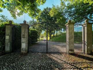 This property boasts a grand entrance with a stunning arched metal gate and stone pillars, creating an elegant and secure feel.