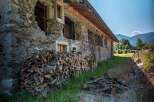 Rustic stone house with woodpile, undergoing renovation.