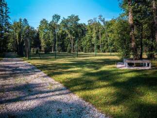 Discover tranquility in this serene park setting, featuring a gravel pathway winding through lush green lawns and mature trees.
