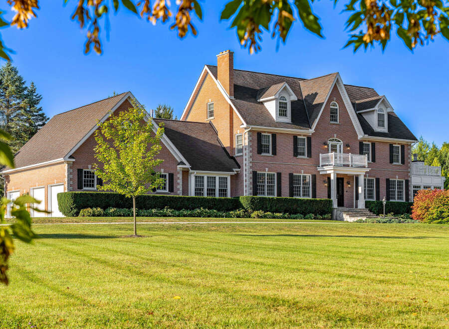 This stunning brick home boasts a spacious layout, complete with a three-car garage and expansive lawn.
