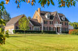 This stunning brick home boasts a spacious layout, complete with a three-car garage and expansive lawn.