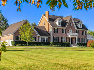 This stunning brick home boasts a spacious layout, complete with a three-car garage and expansive lawn.
