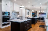 This stunning kitchen boasts a spacious island with marble countertops and dark cabinetry, complemented by high-end Miele appliances.