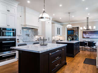 This stunning kitchen boasts a spacious island with marble countertops and dark cabinetry, complemented by high-end Miele appliances.
