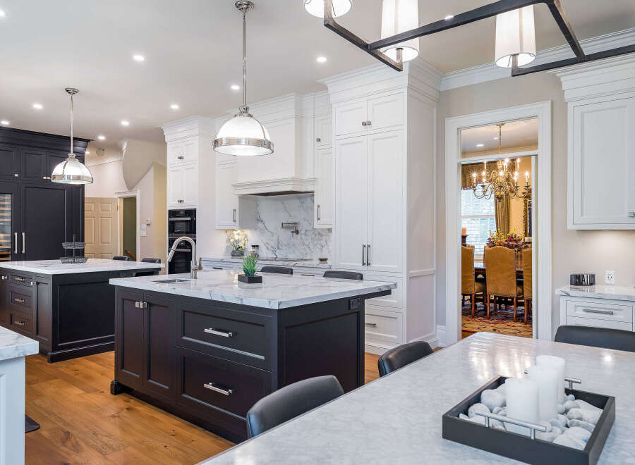 This stunning kitchen boasts a spacious island with marble countertops, complemented by dark cabinetry and high-end appliances.