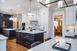 This stunning kitchen boasts a spacious island with marble countertops, complemented by dark cabinetry and high-end appliances.