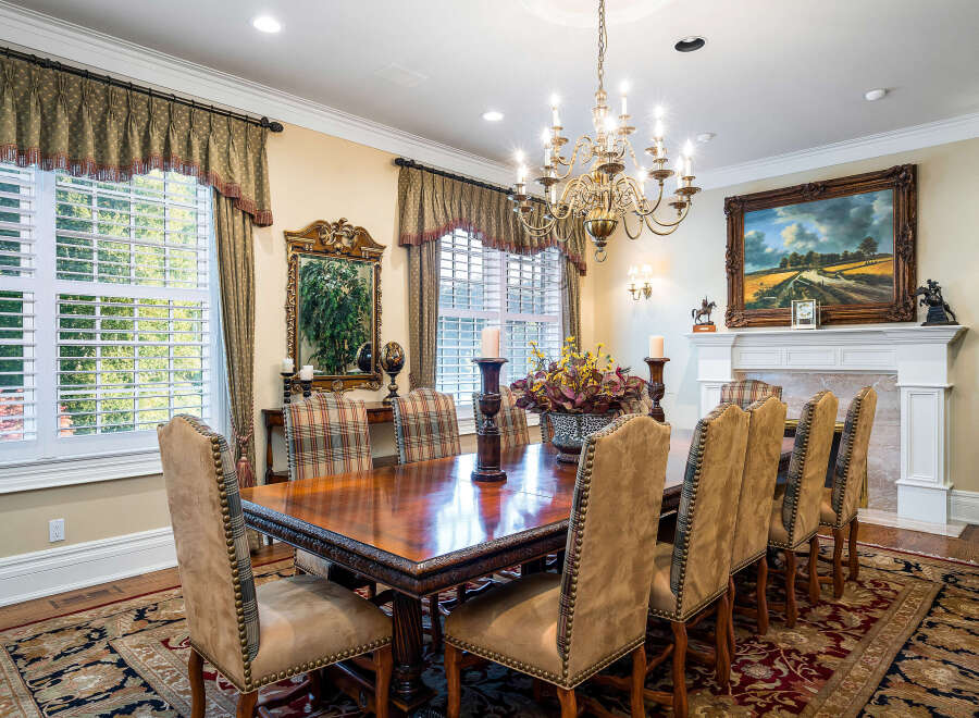 This elegant dining room boasts a stunning chandelier, hardwood floors, and a large antique dining table.