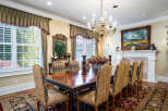 This elegant dining room boasts a stunning chandelier, hardwood floors, and a large antique dining table.