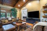This stunning living room boasts a gorgeous wood-beamed ceiling, large windows offering ample natural light, and a cozy leather seating area perfect for relaxation.