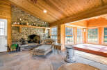 This sunroom boasts a stunning stone fireplace, vaulted wood ceilings, and expansive windows offering abundant natural light.