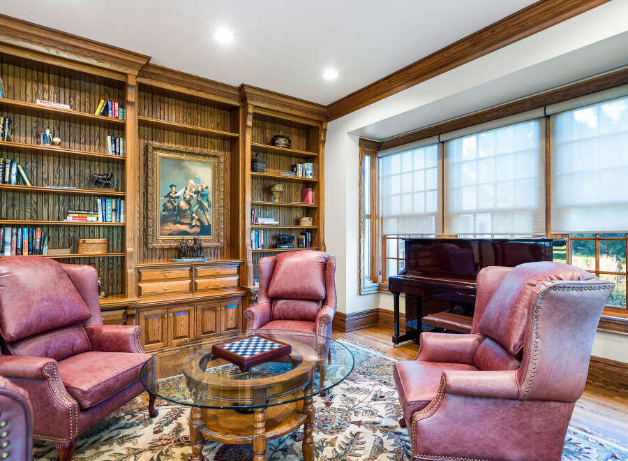 This luxurious library boasts built-in bookshelves, a stunning painting, and comfortable leather armchairs.