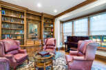 This luxurious library boasts built-in bookshelves, a stunning painting, and comfortable leather armchairs.