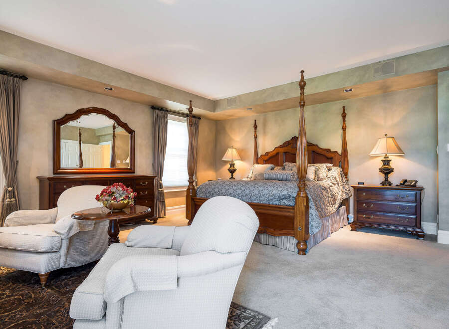 Luxurious master bedroom with a four-poster bed, plush carpeting, and elegant furnishings.