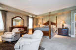 Luxurious master bedroom with a four-poster bed, plush carpeting, and elegant furnishings.
