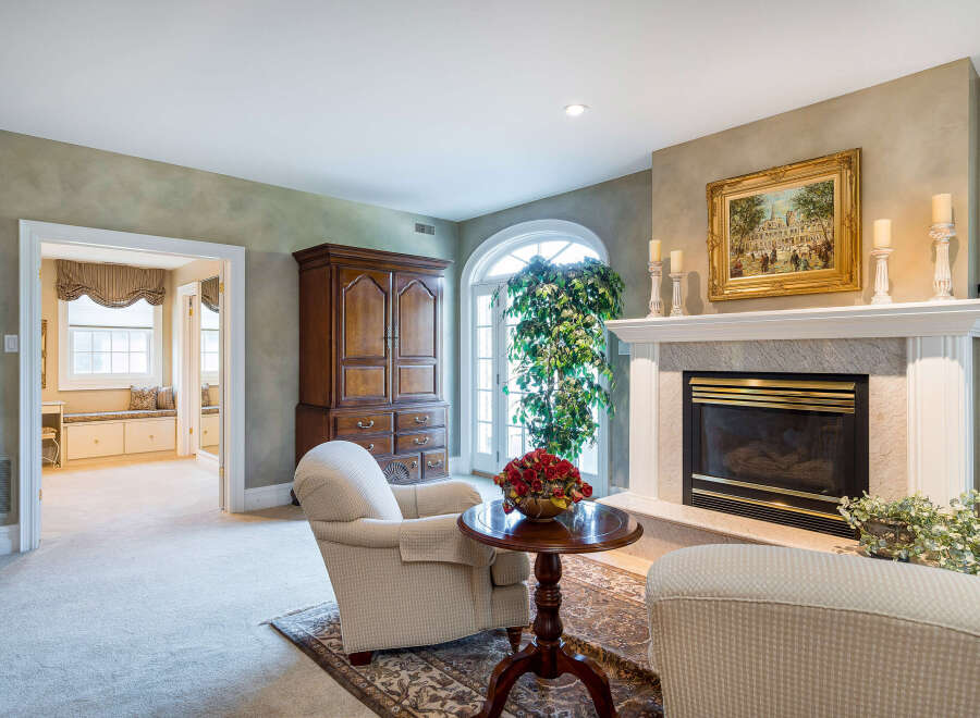 This luxurious living room boasts a stunning marble fireplace, complemented by elegant furnishings and a large arched window that floods the space with natural light.