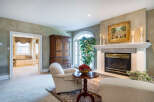 This luxurious living room boasts a stunning marble fireplace, complemented by elegant furnishings and a large arched window that floods the space with natural light.