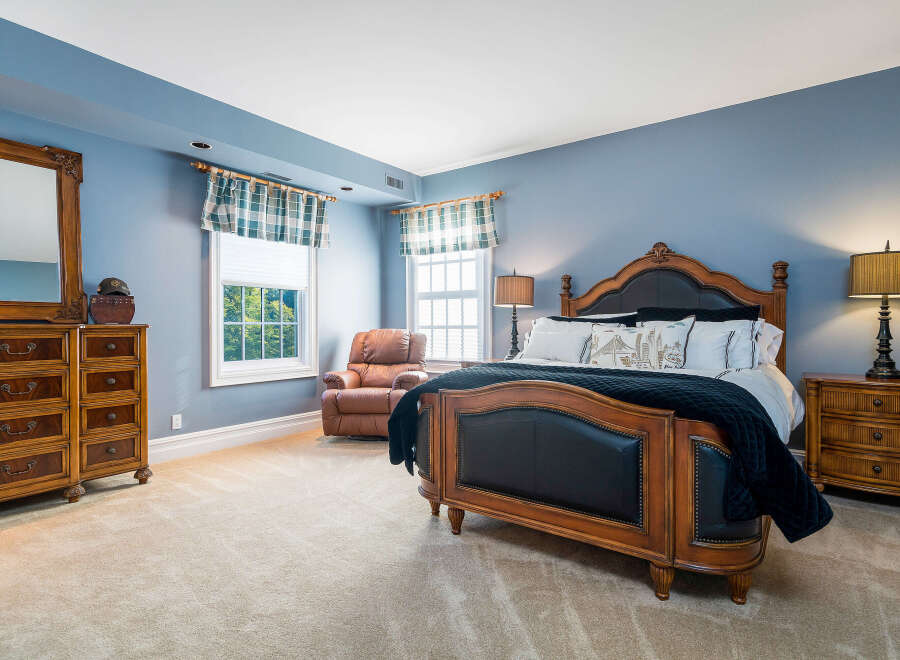 This stunning bedroom boasts a luxurious, wooden bed frame with a plush black headboard, complemented by a cozy leather recliner.