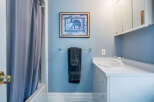 This charming bathroom boasts a light blue color scheme, complemented by white vanity and fixtures.