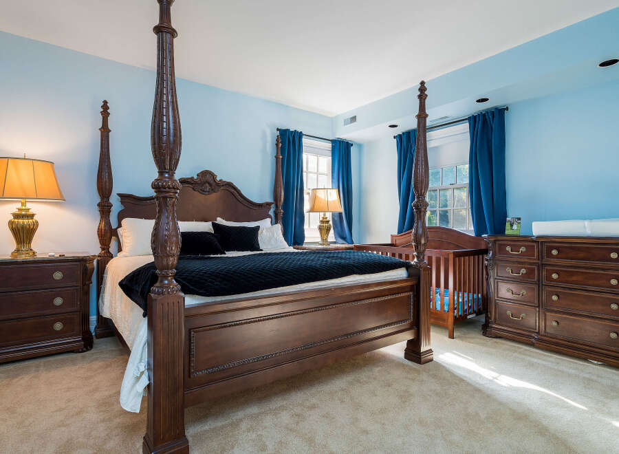This beautiful bedroom boasts a stunning four-poster bed, complemented by rich wood furniture and plush carpeting.