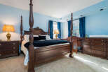This beautiful bedroom boasts a stunning four-poster bed, complemented by rich wood furniture and plush carpeting.