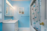 This charming bathroom boasts a light blue color scheme, complemented by white fixtures and a butterfly-themed shower curtain.