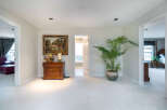 Elegant hallway with plush carpeting, showcasing a charming wooden dresser and a vibrant potted plant.
